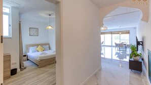 A modern hotel room with a bed, bedside table, and a view of the outdoor area. - A lovely, central 2BR penthouse with large outdoor (L-Iklin)