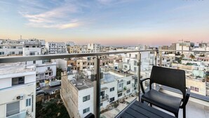 Ein Balkon mit Blick auf eine Stadtlandschaft, ein Stuhl und das Logo '360 ESTATES'.
