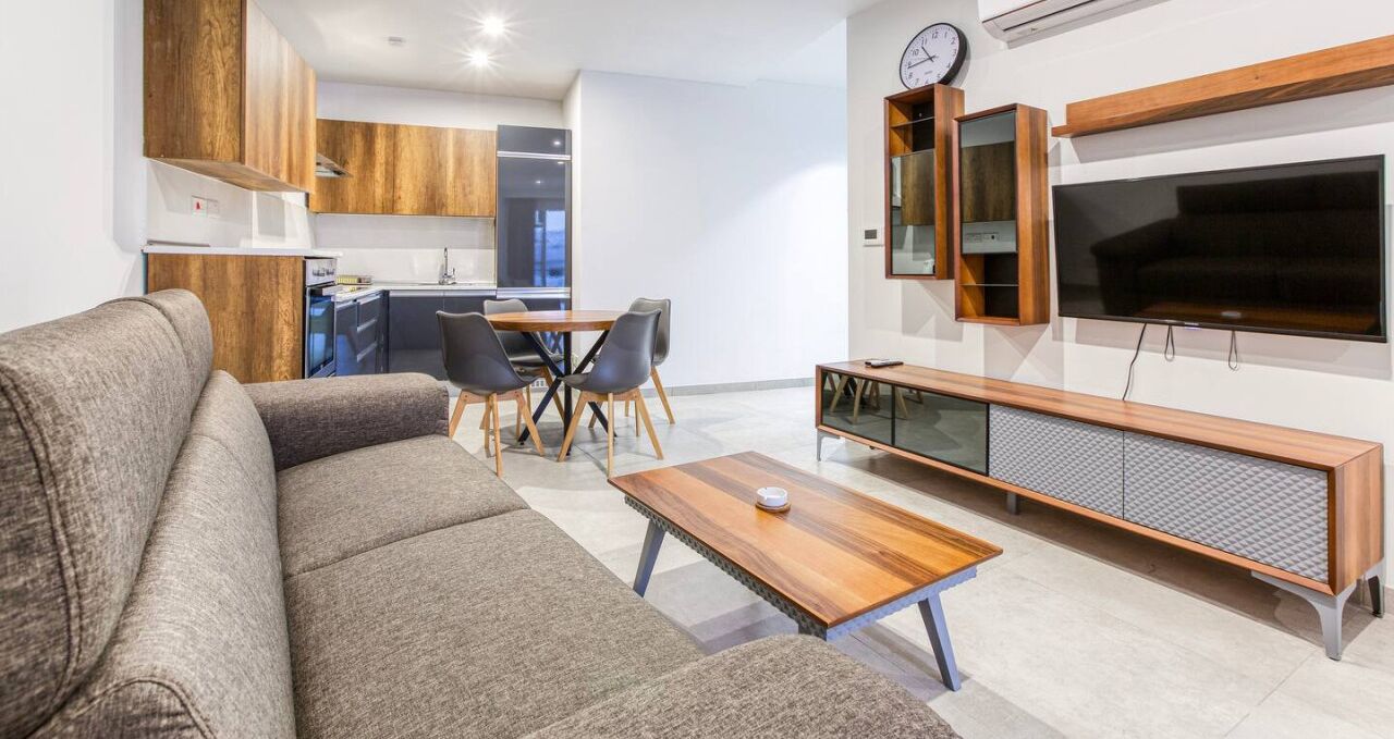 A modern living room with a sofa, coffee table, and TV stand.