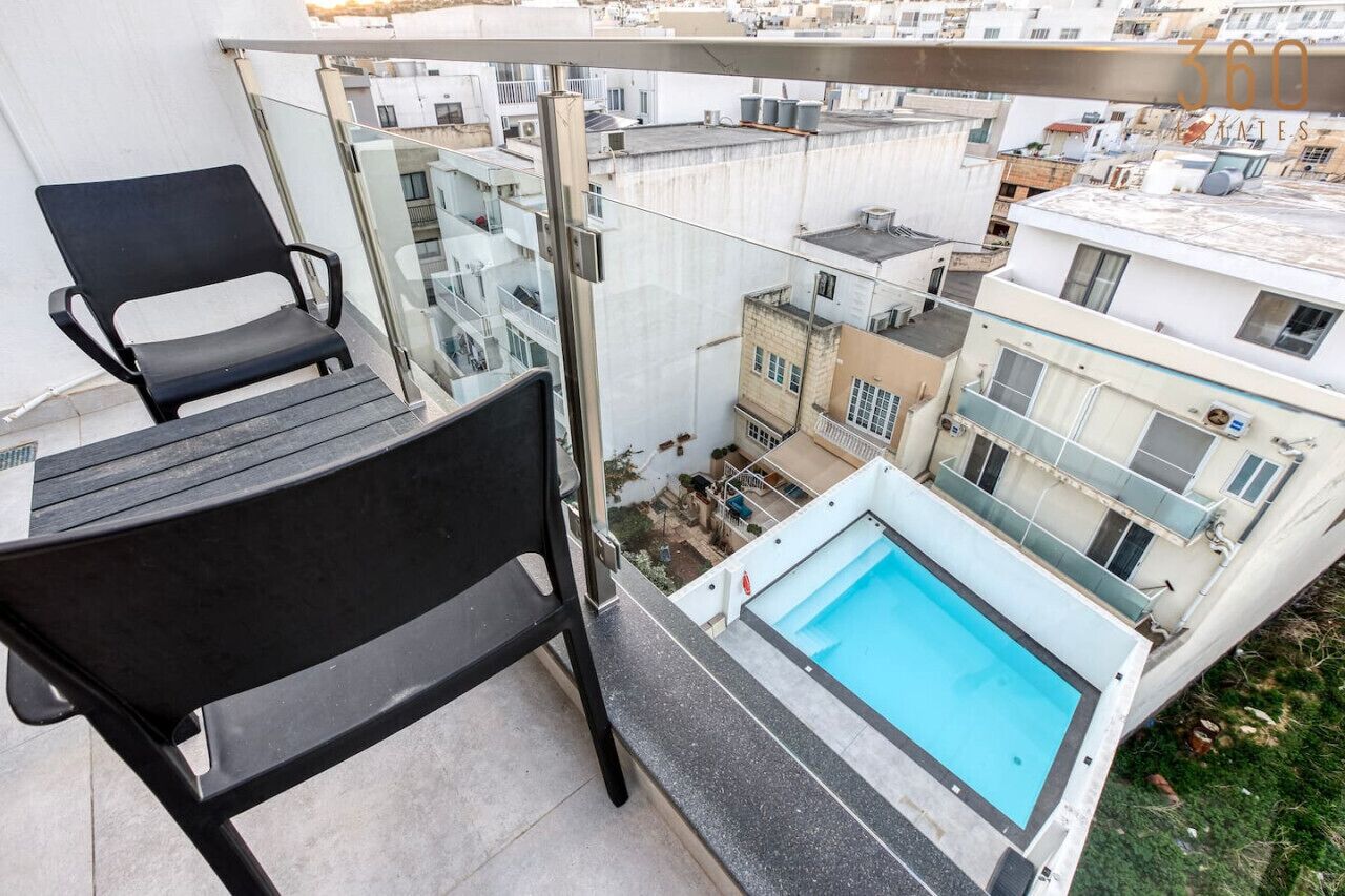 A balcony with a black chair and a small pool.
