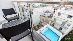 Ein Balkon mit einem schwarzen Stuhl und einem kleinen Pool.