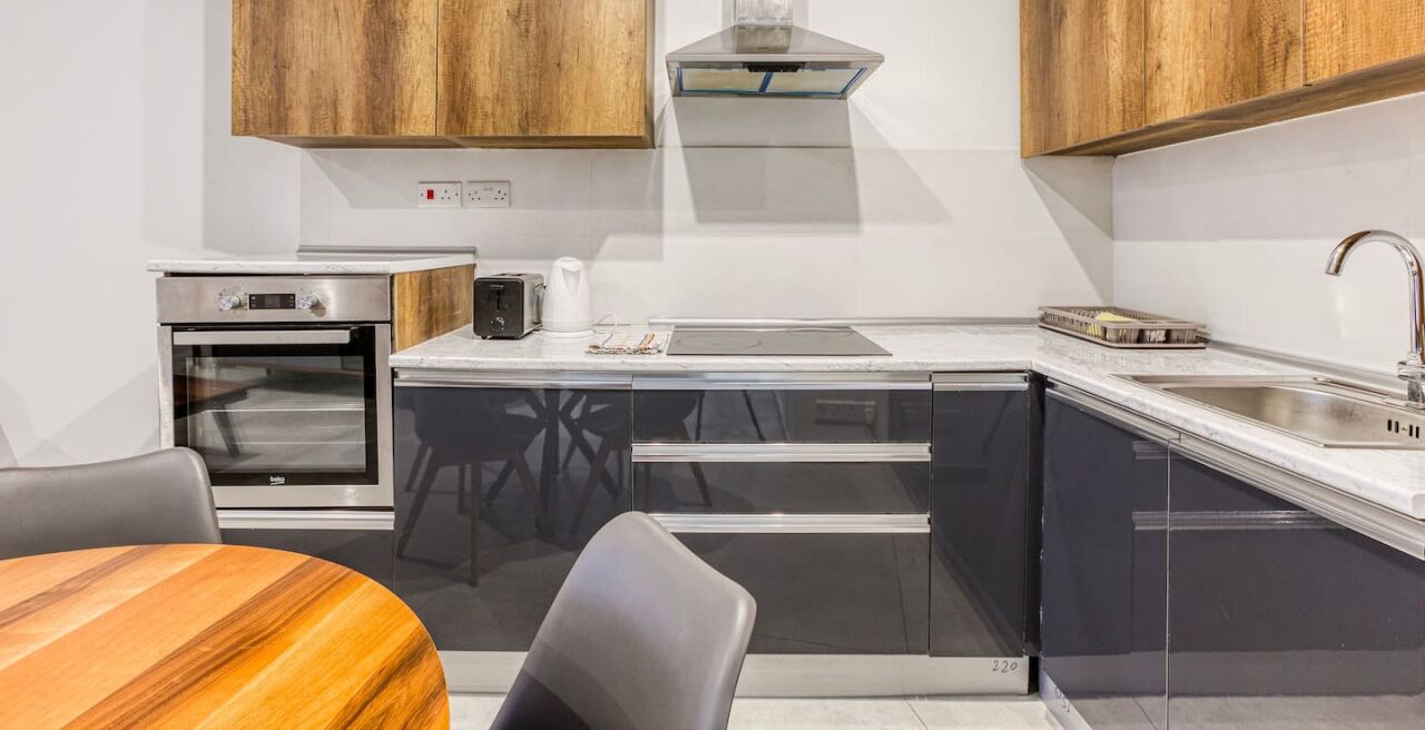 Une cuisine compacte avec des meubles en bois, un four encastré, un grille-pain et un évier.