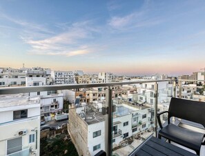 A balcony with a view of a cityscape, a chair, and the logo "360 ESTATES". - POOL access and a beautiful 1BR APT in Swieqi (Is-Swieqi)