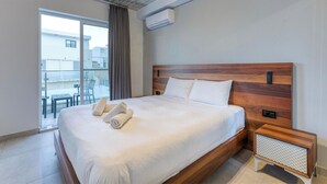 A hotel room with a large bed, a wooden headboard, a bedside table, and a view of the outside. - A fully equipped APT with private balcony & Pool (Is-Swieqi)