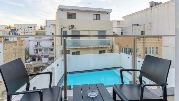 A rooftop terrace with a pool, two chairs, and a table. - A fully equipped APT with private balcony & Pool (Is-Swieqi)