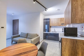 A modern kitchen with a built-in oven, a microwave, and wooden cabinets. - A fully equipped APT with private balcony & Pool (Is-Swieqi)