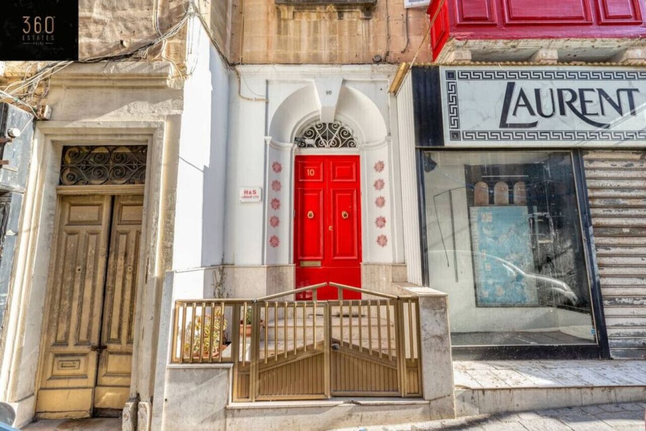 Facciata di un edificio con una porta rossa, un'insegna per '360 Estates' e un negozio 'Laurent'.