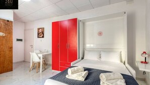 A hotel room with a large bed, a red wardrobe, a desk, and a chair. - Urban studio room in Sliema Ferries with Views (Tas-Sliema)