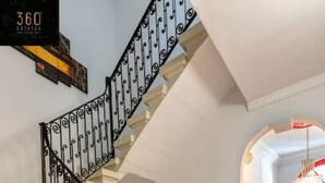 A staircase with ornate black railings and beige steps, leading to a bright red door. - Urban studio room in Sliema Ferries with Views (Tas-Sliema)