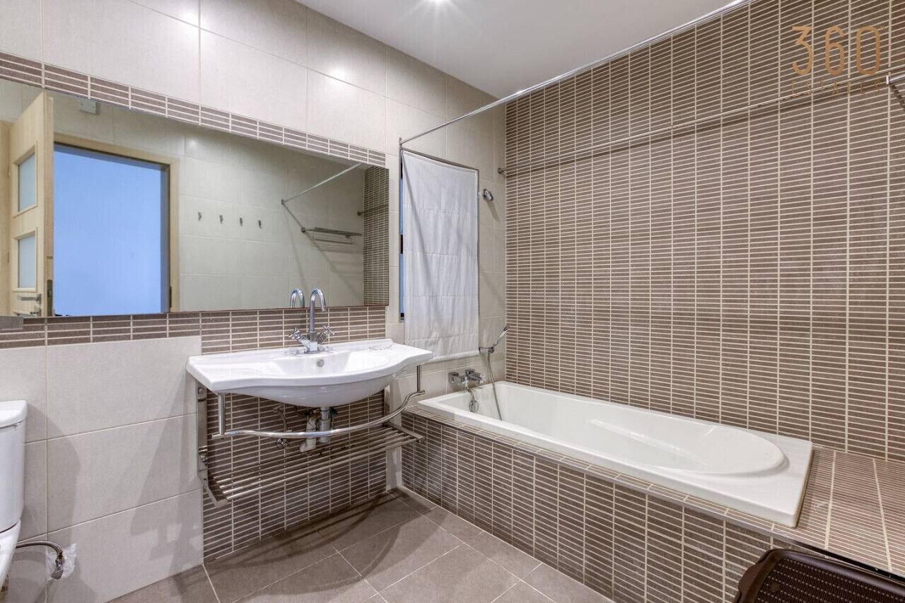 Une salle de bain moderne avec un lavabo blanc, une baignoire et un grand miroir.
