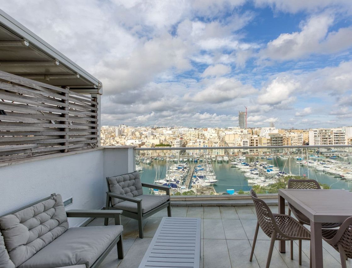 A balcony with a view of a marina and cityscape.