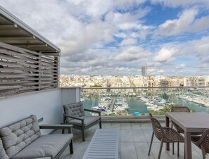 Een balkon met uitzicht op een jachthaven en stadsgezicht.
