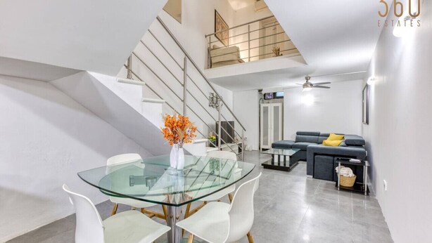 A modern interior with a glass dining table, white chairs, a grey sofa, and a staircase. - An amazing 2BR home with a special private rooftop (Tas-Sliema)