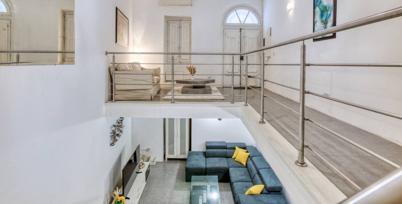 A modern interior with a staircase, a sofa set, and a dining area.