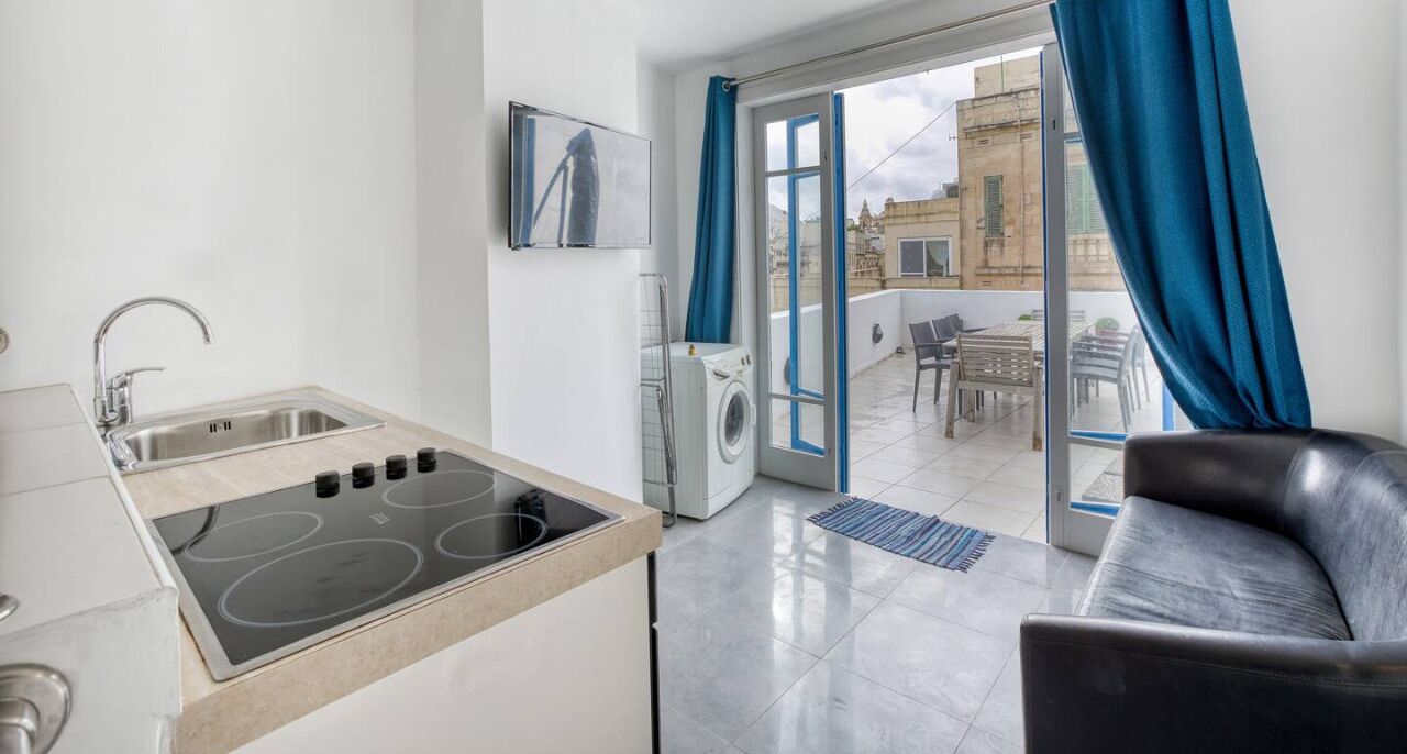 Una cucina moderna con piano cottura integrato, lavello e lavatrice. C'è un balcone con vista sulla città.