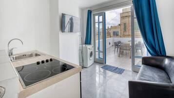 Una cucina moderna con piano cottura integrato, lavello e lavatrice. C'è un balcone con vista sulla città.