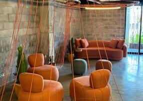 Un interno moderno con sedute arancioni, una pianta di cactus e una lampada a sospensione.