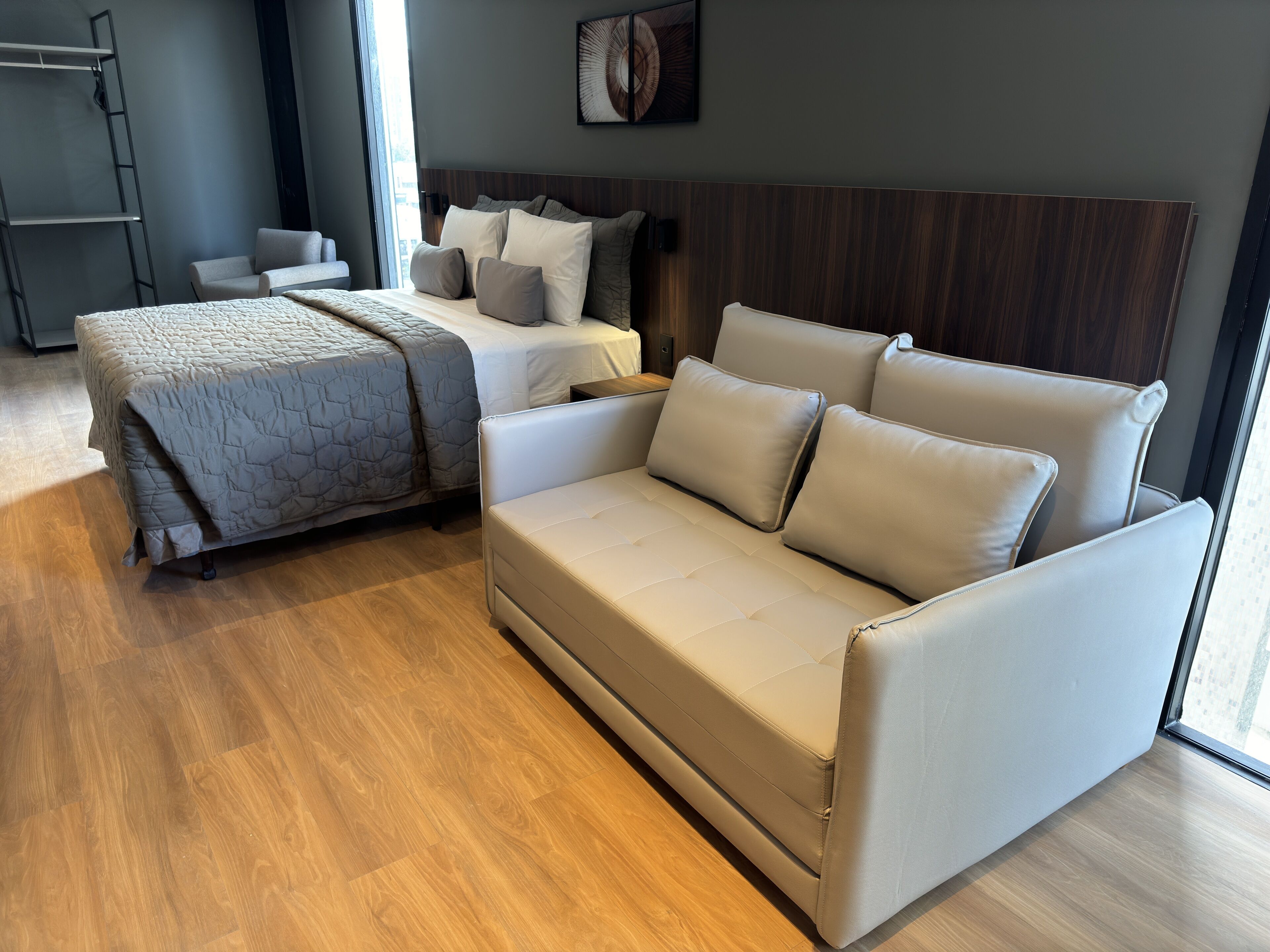 Un dormitorio moderno con una cama, un sofá y piso de madera.