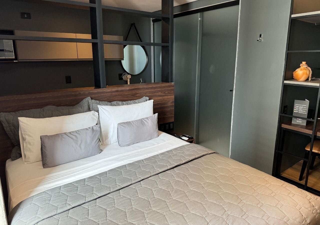 Une chambre à coucher moderne avec un grand lit, une tête de lit en bois, une table de chevet, un miroir et une armoire.