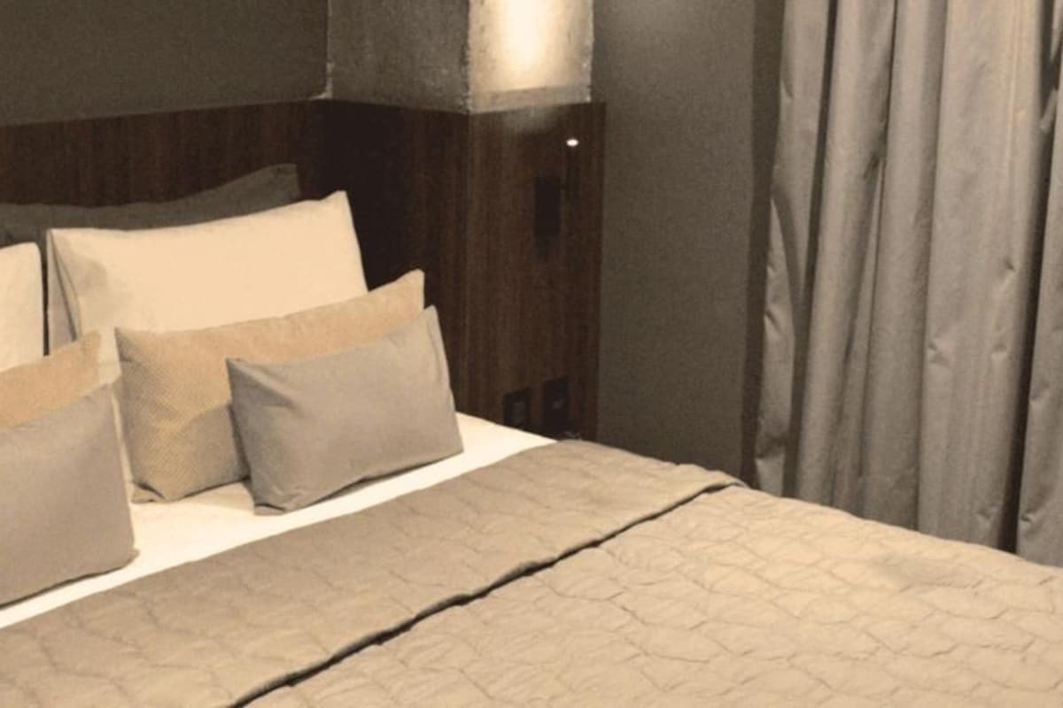 Una cama bien hecha con un edredón gris y varias almohadas.