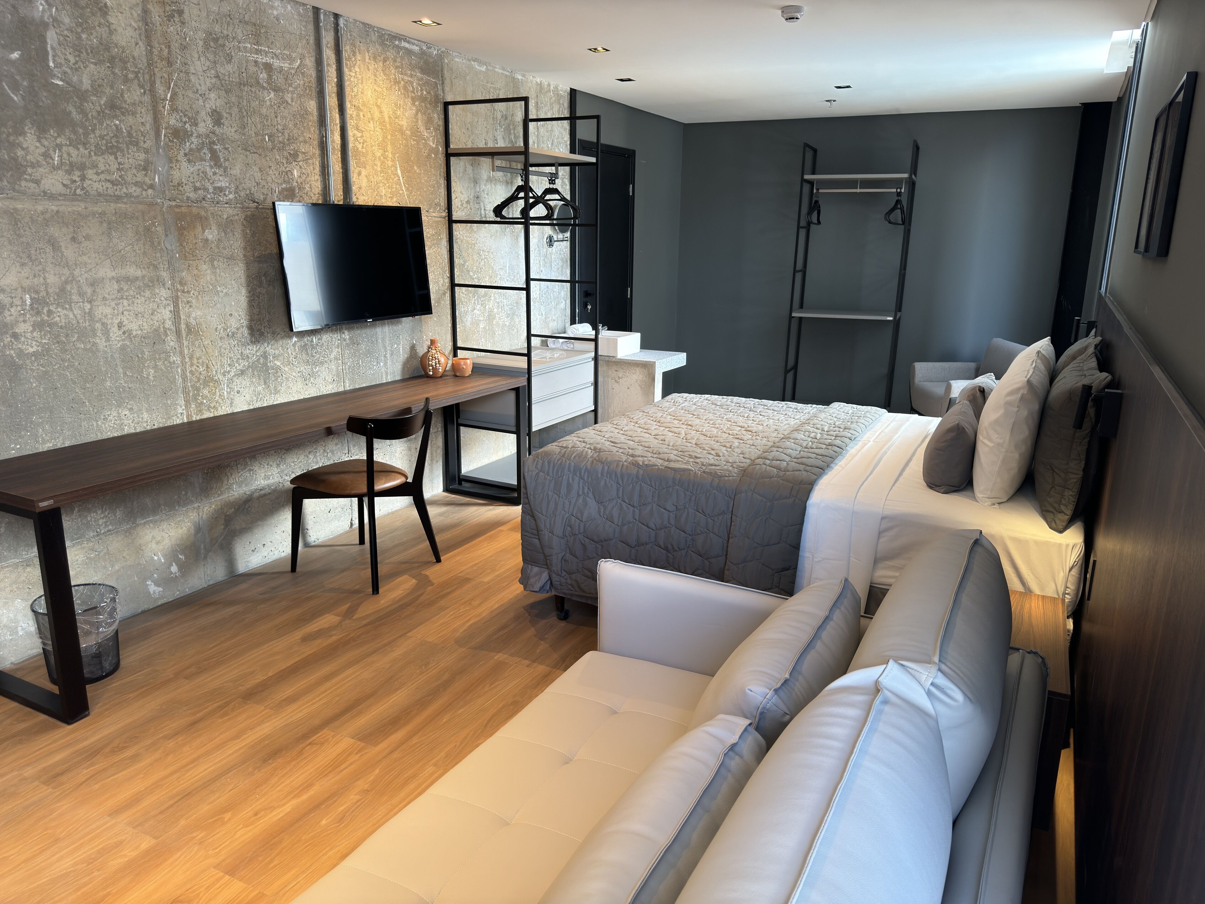 Une chambre à coucher moderne avec un lit, un canapé, un bureau et un téléviseur.