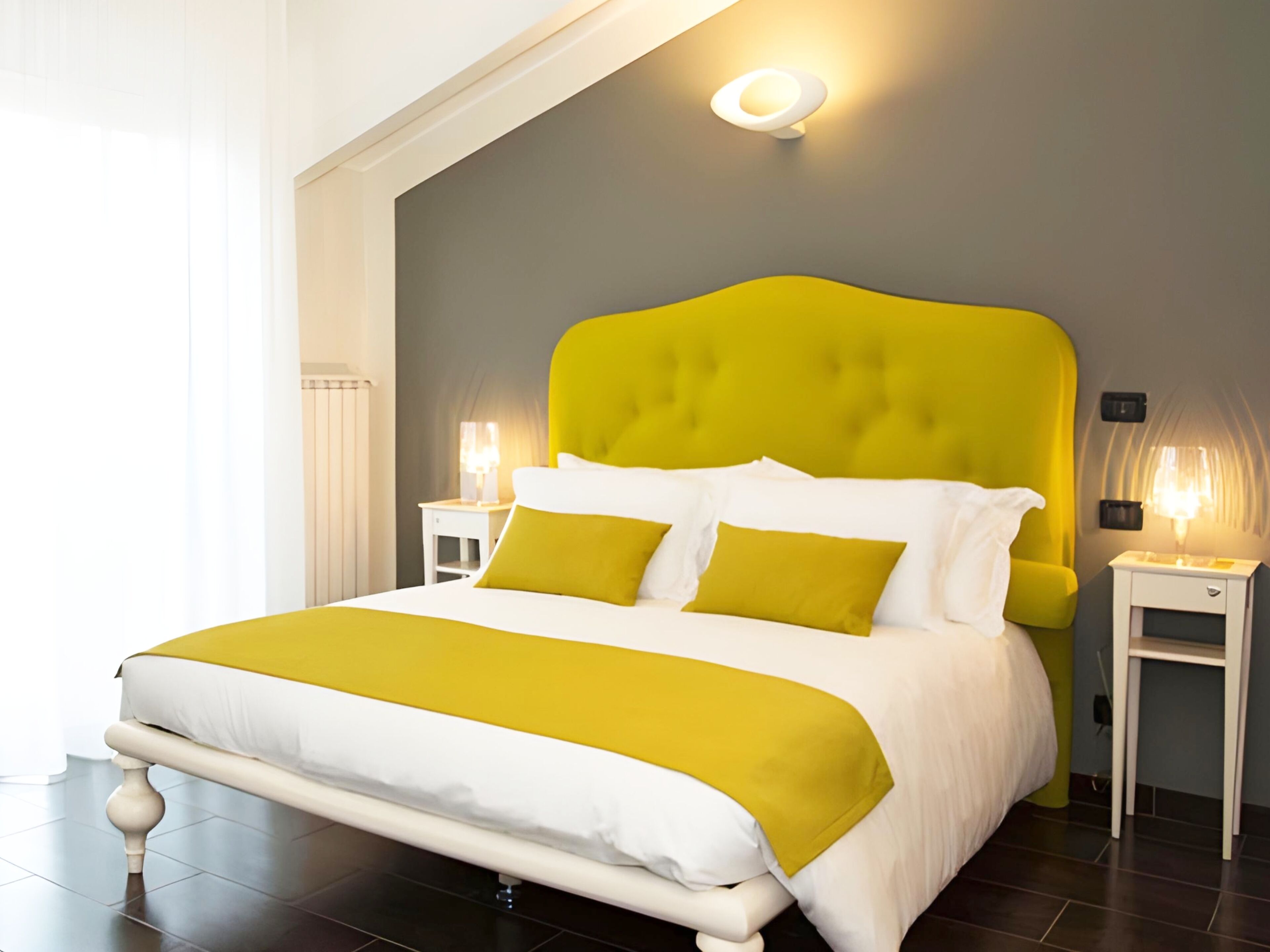 Un lit avec une couvre-lit blanche et jaune, une tête de lit jaune vif et deux lampes de chevet.