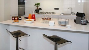 A modern kitchen with a central island, bar stools, a coffee machine, and a variety of food items. - Pepe's Home B&B (Nichelino)
