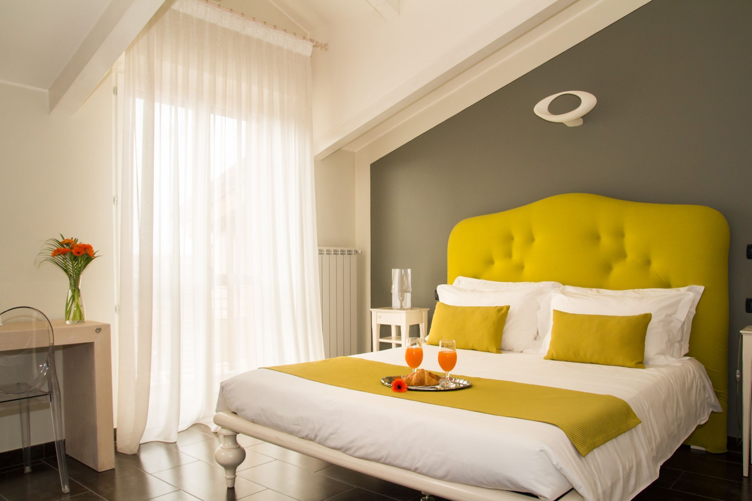 A hotel room with a bed, a bedside table, a chair, and a desk.