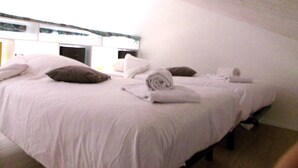 A single-bed room with a high ceiling and a sloped roof.