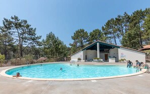 Piscina com área coberta, rodeada por árvores.