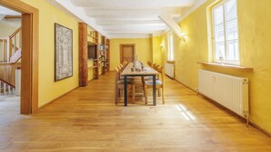 A spacious room with a long wooden table and chairs, a bookshelf, and a window with a view. - Burg Großbodungen - Ferien im Schloß - Familien & Gruppen Mitten in Deutschland (Am Ohmberg)