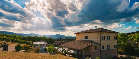 A building with a tiled roof, a small garden, and a view of the surrounding landscape.