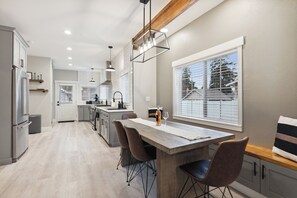 Une cuisine moderne dotée d’un îlot central, de luminaires suspendus et offrant une vue sur l’extérieur grâce à de grandes fenêtres.