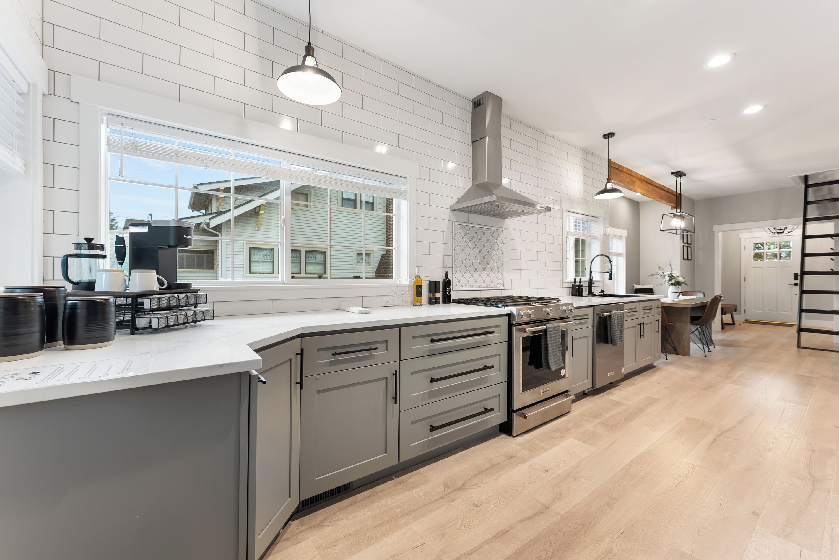 A modern kitchen with a large island, stainless steel appliances, and a view of the outside.