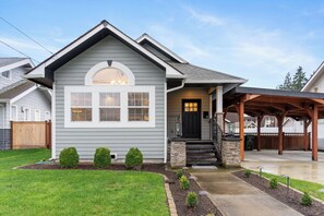 A residential house with a front porch, a stone column, and a covered patio area.