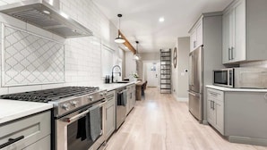 Una cocina moderna con electrodomésticos de acero inoxidable, salpicadero de azulejos blancos y suelo de madera clara.