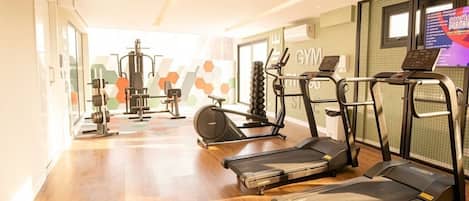 A gym with treadmills, weight machines, and a mirrored wall.