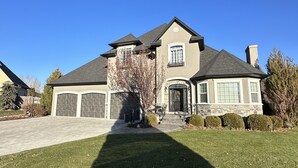 A two-story house with a stone facade, a large garage, and a well-maintained lawn. - Idaho Falls 6bed4bath Exquisite Home (Idaho Falls)