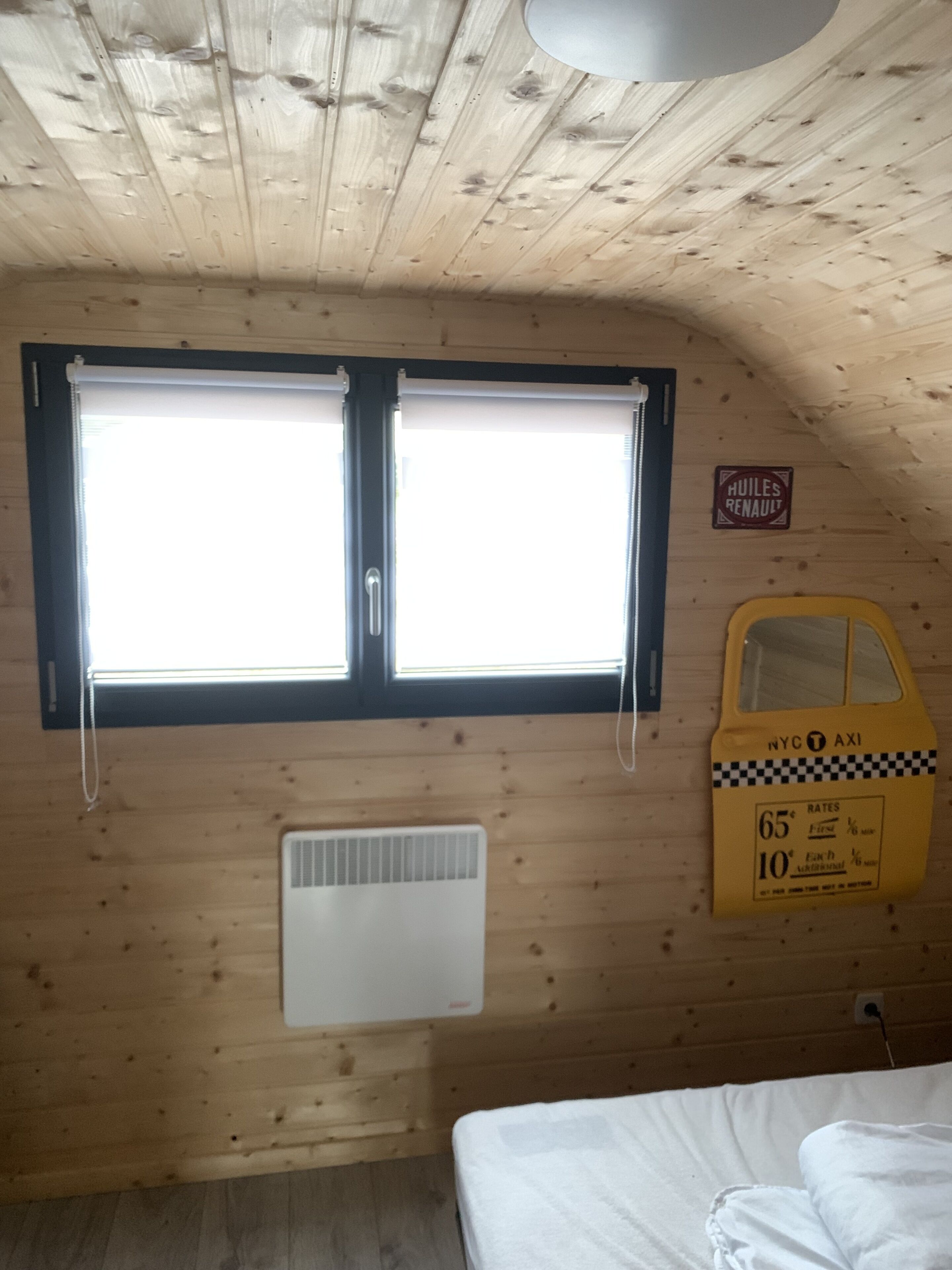 Une pièce de cabane en bois avec une fenêtre, un radiateur et un panneau jaune indiquant « taxi ».