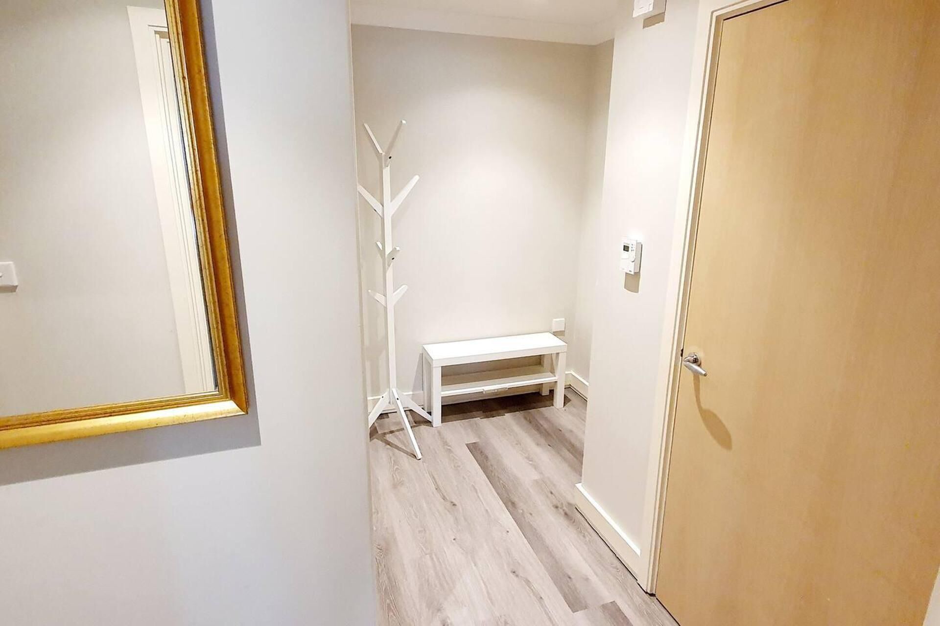 Un corridoio con una panca bianca, un appendiabiti e una porta in legno.