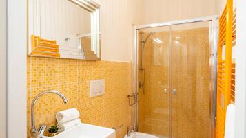 Une salle de bain équipée d’un lavabo, d’un miroir et d’un espace douche.