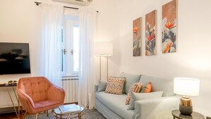 A modern living room with a sofa, a pink armchair, a coffee table, and a TV. - Genteel Home Contessa Matilde (Pisa)