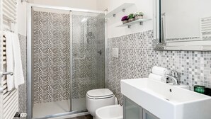 A modern bathroom with a glass-enclosed shower, a white toilet, and a large sink with a mirror above. - Genteel Home Contessa Matilde (Pisa)