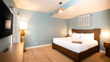 Habitación de hotel moderna con cama de madera, televisión de pantalla plana, mesita de noche y una obra de arte colgada en la pared.