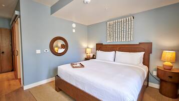A bedroom with a large bed, a wooden wardrobe, a round mirror, and a wall-mounted artwork.