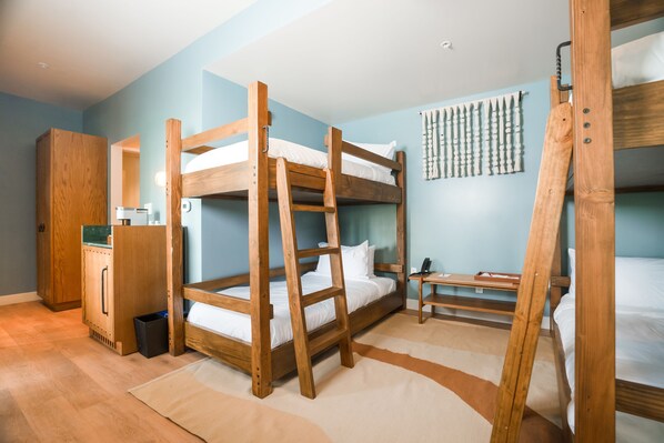 Dormitorio con literas, una escalera de madera, un escritorio y un armario.