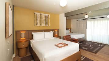 A hotel room with a large bed, two bedside tables with lamps, a headboard with a decorative panel, a brown rug, and a window with curtains.