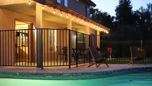 A poolside area with a covered patio, outdoor furniture, and string lights. - New! Spacious 3K sq ft 4BD/3Bath + Pool (Bakersfield)