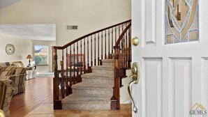 A spacious living room with a wooden staircase leading to a second floor. - New! Spacious 3K sq ft 4BD/3Bath + Pool (Bakersfield)