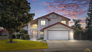 A two-story house with a garage, a well-maintained lawn, and a large tree in the front yard. - New! Spacious 3K sq ft 4BD/3Bath + Pool (Bakersfield)